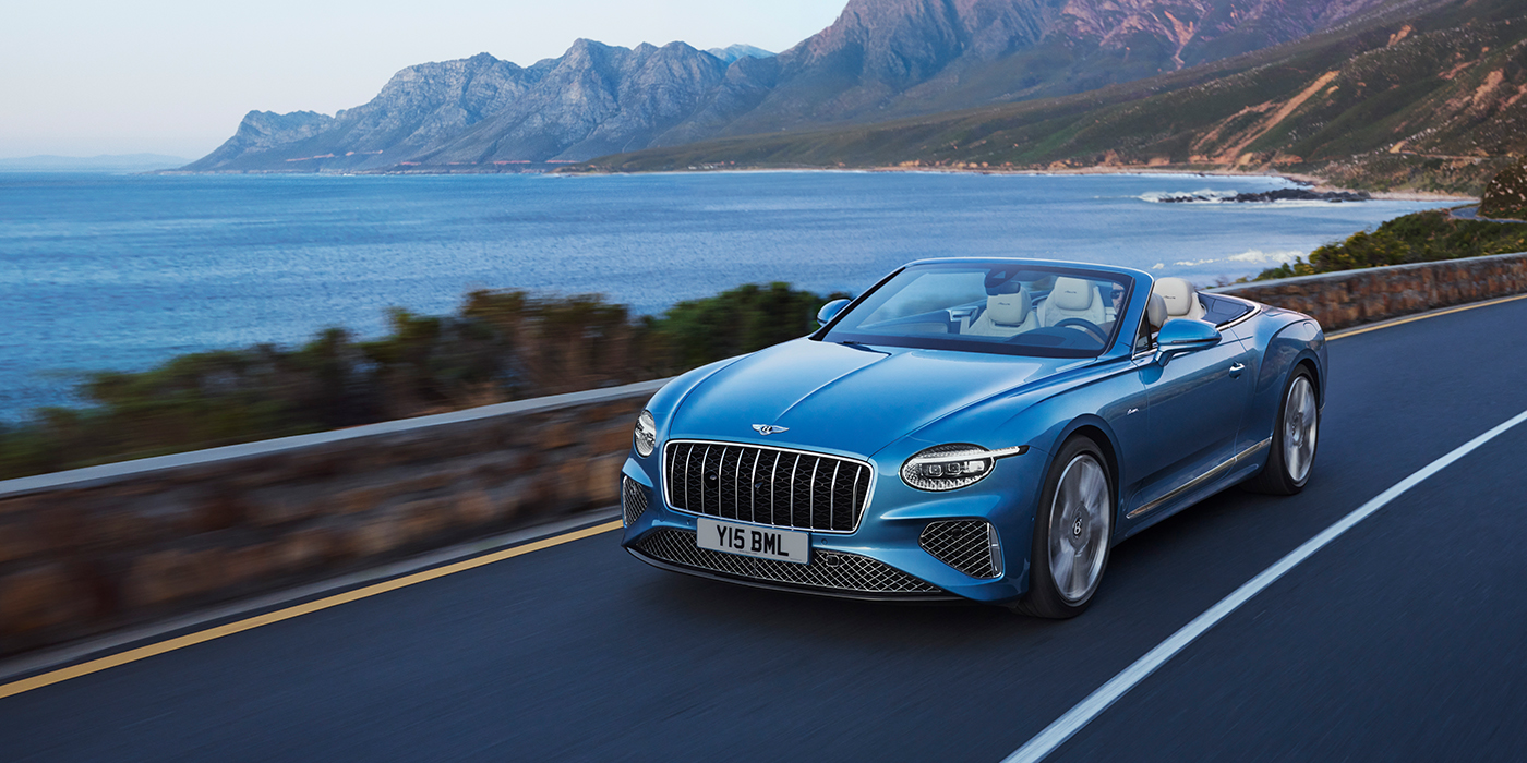 Bentley Polanco New Bentley Continental GTC Azure convertible in Light Windsor blue paint with 22 inch Azure wheels and chrome grill, driving dynamically by the sea