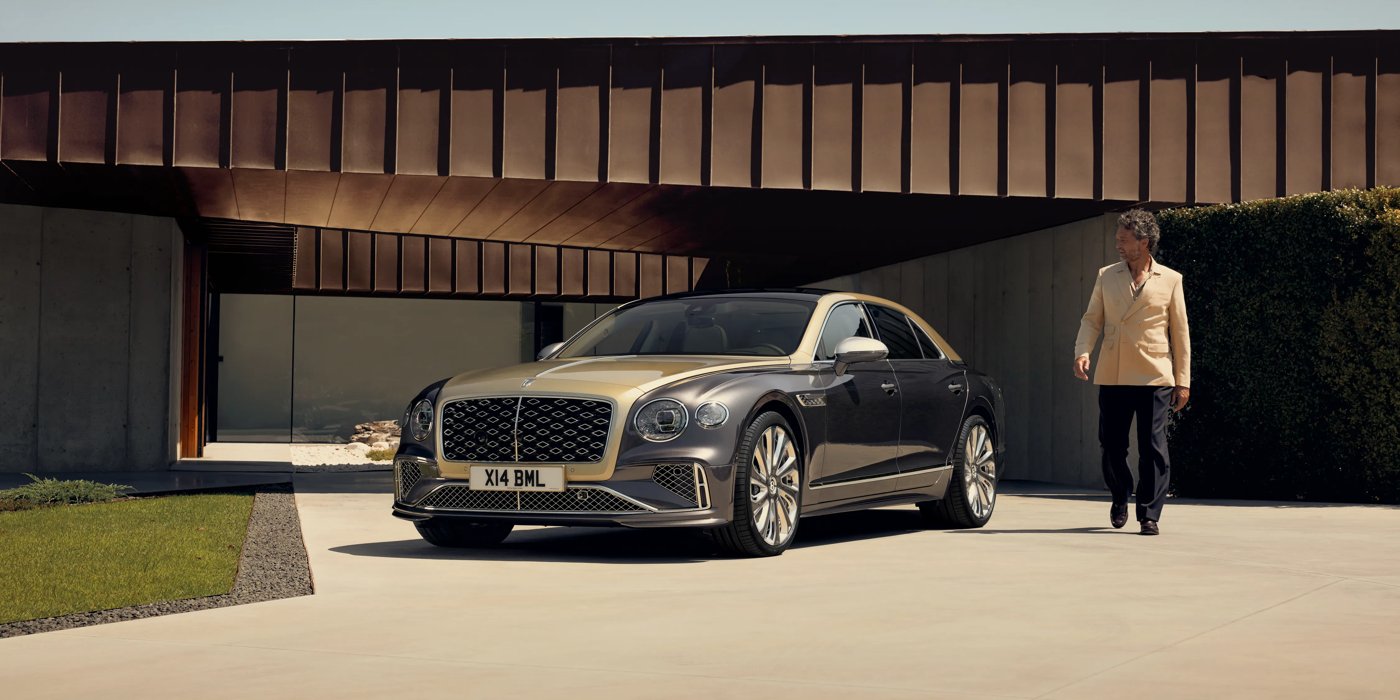 Bentley Polanco Bentley New Flying Spur Mulliner V8 hybrid sedan front three quarters in Rose Gold over Magnetic paint, parked near modern home