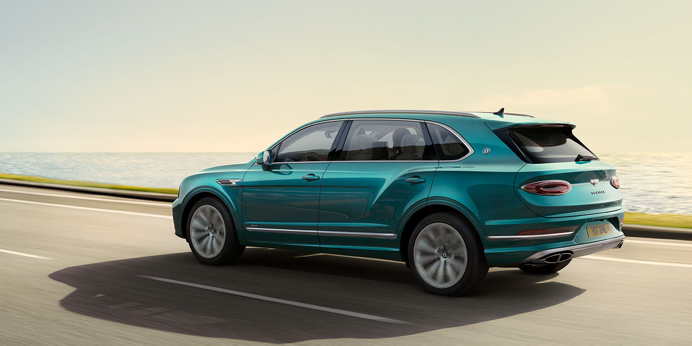 Bentley Polanco Bentley Bentayga Extended Wheelbase Azure luxury SUV rear three quarter in Topaz Blue by Mulliner paint, driving on an ocean road.