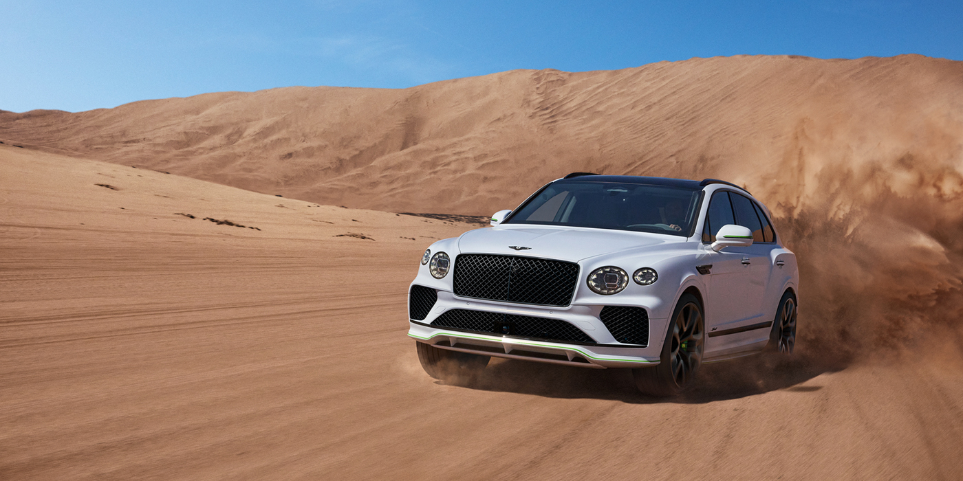 Bentley Polanco Bentley Bentayga Speed SUV front three quarter in Snow Quarts Pearlescent by Mulliner white paint driving dynamically through the desert