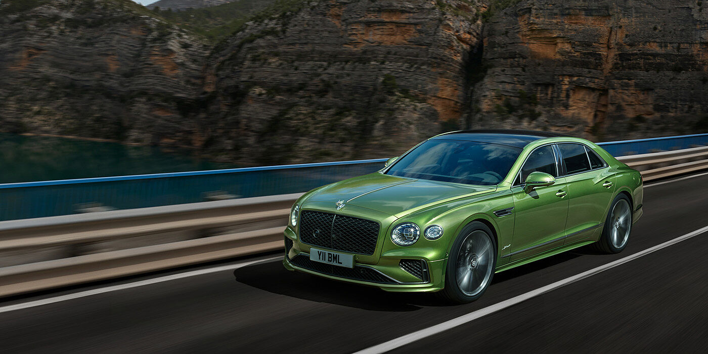 Bentley Polanco Bentley New Flying Spur Speed v8 hybrid sedan driving dynamically on a mountain road in Tourmaline Green paint