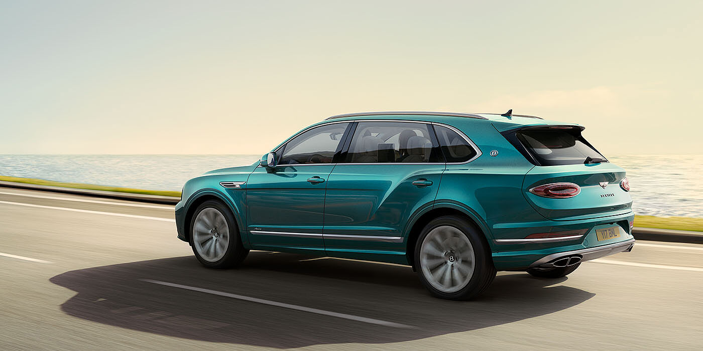 Bentley Polanco Bentley Bentayga Extended Wheelbase Azure luxury SUV rear three quarter in Topaz Blue by Mulliner paint, driving on an ocean road.