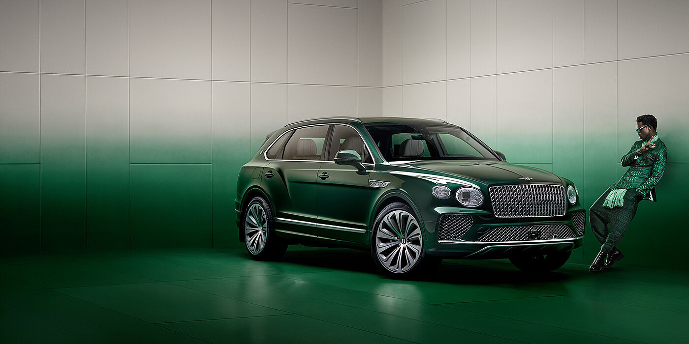 Bentley Polanco Wisdom K leans against wall next to Bentley Bentayga Extended Wheelbase Atelier Edition SUV in Light Emerald green paint