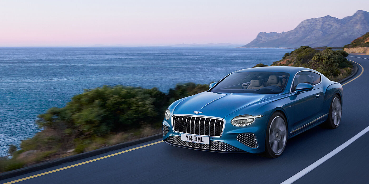 Bentley Polanco New Bentley Continental GT Azure coupe in Light Windsor blue paint with 22 inch Azure wheels and chrome grill, driving dynamically by the sea