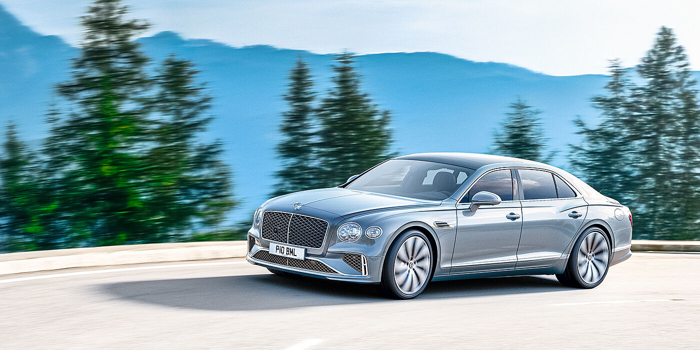 Bentley Polanco New Bentley Flying Spur sedan side view in Silverlake paint with ten spoke wheels and chrome matrix grille driving dynamically on a mountain road