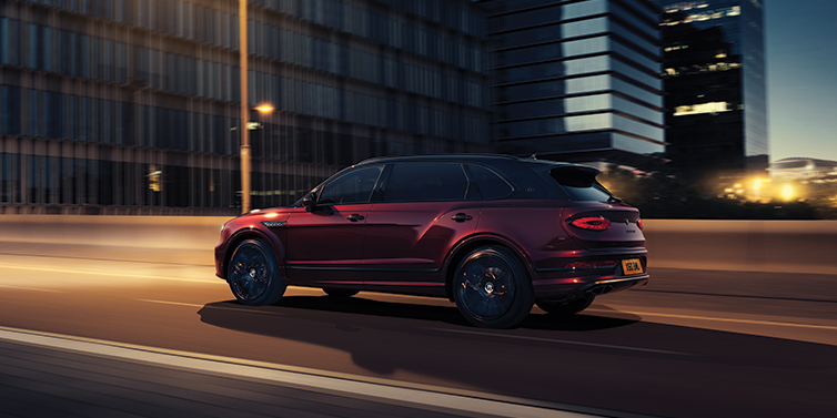 Bentley Polanco Bentley Bentayga Extended Wheelbase Mulliner SUV in Cricket Ball red paint driving dynamically in city at night
